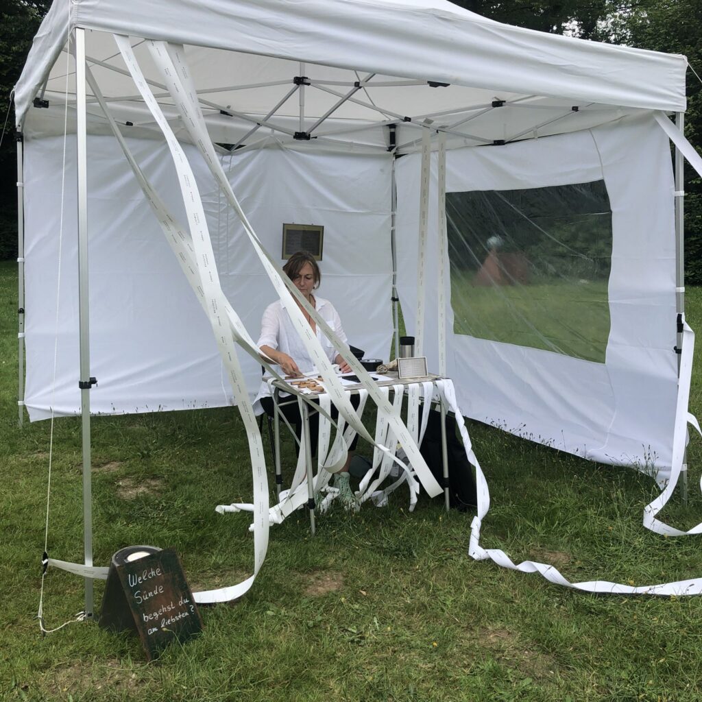 Angelika Sinn sitzt in einem Garten und bestempelt Papierbahnen.